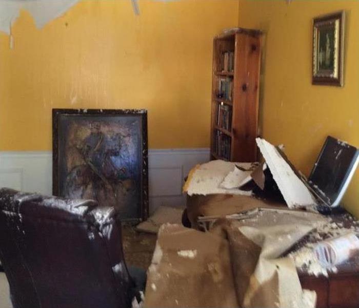 A room with debris and a celling falling out after a storm blew through
