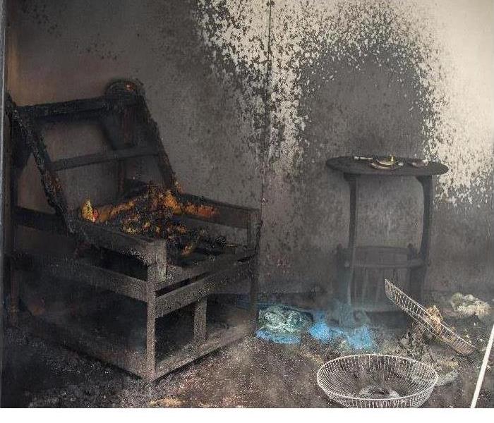 A fire damaged room with burnt chair and side table. 