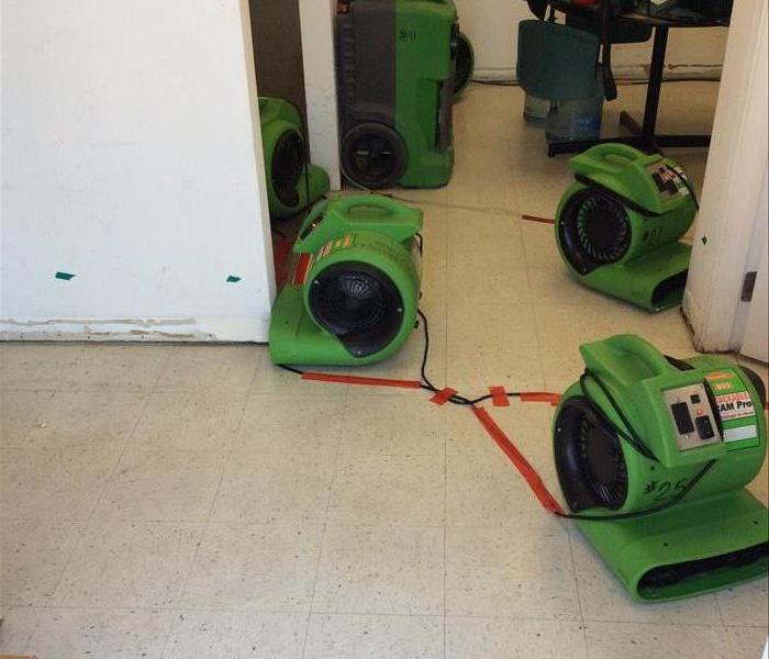 Air movers drying a wet office wall.