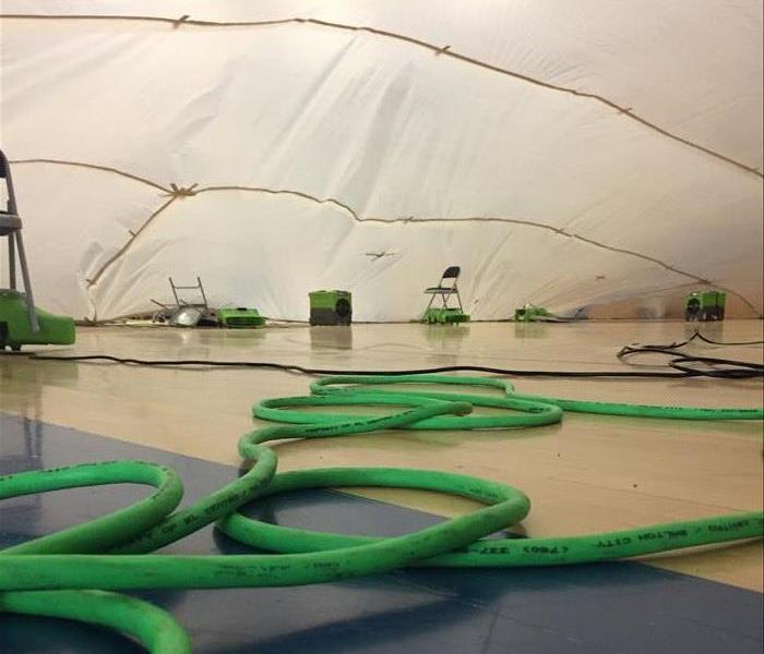 Green hoses, drying equipment, and a rigged containment tent for drying a gymnasium